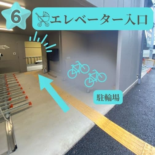 : ビル右奥にあるエレベーターと駐輪場入口。ベビーカーや自転車でお越しの方はこちらをご利用ください。